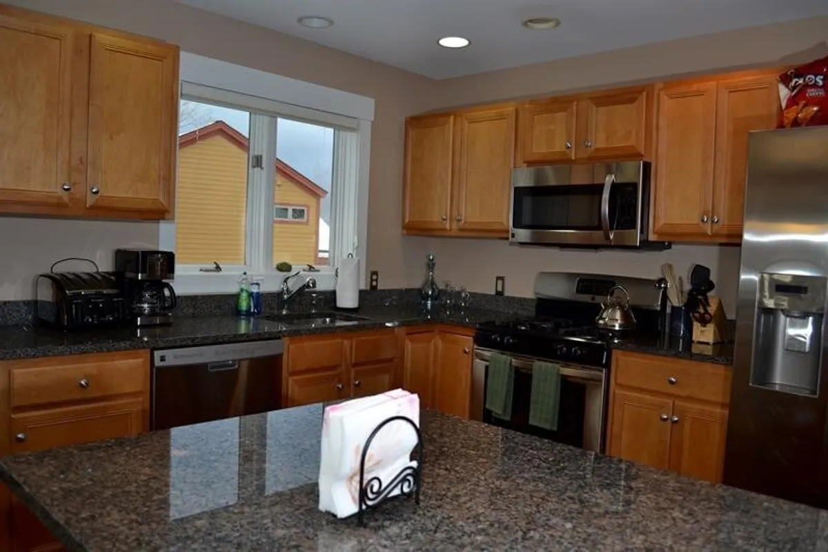 A spacious, modern kitchen with granite countertops, stainless steel appliances, and rich wooden cabinets. The scene exudes warmth and functionality, highlighting ample counter space and the kitchen's role as a hub for cooking and entertaining.