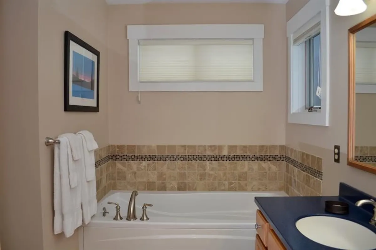 A serene bathroom scene centered on a freestanding bathtub, complemented by framed artwork and neatly folded towels. The space is softly lit, evoking relaxation and self-care—an ideal retreat after outdoor adventures.