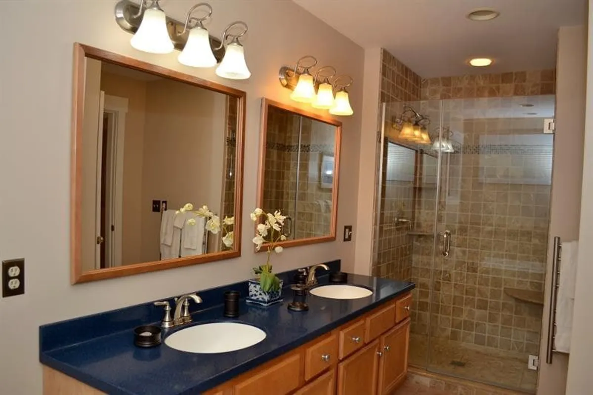 A modern bathroom with double vanity sinks, elegant framed mirrors, and a glass shower enclosure. The space is bathed in natural light, creating an inviting and functional area for morning routines and relaxation.